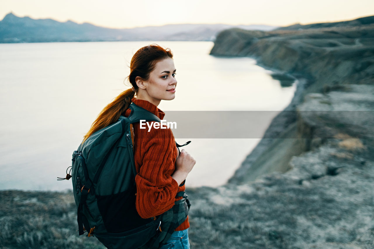 YOUNG WOMAN STANDING AT SHORE