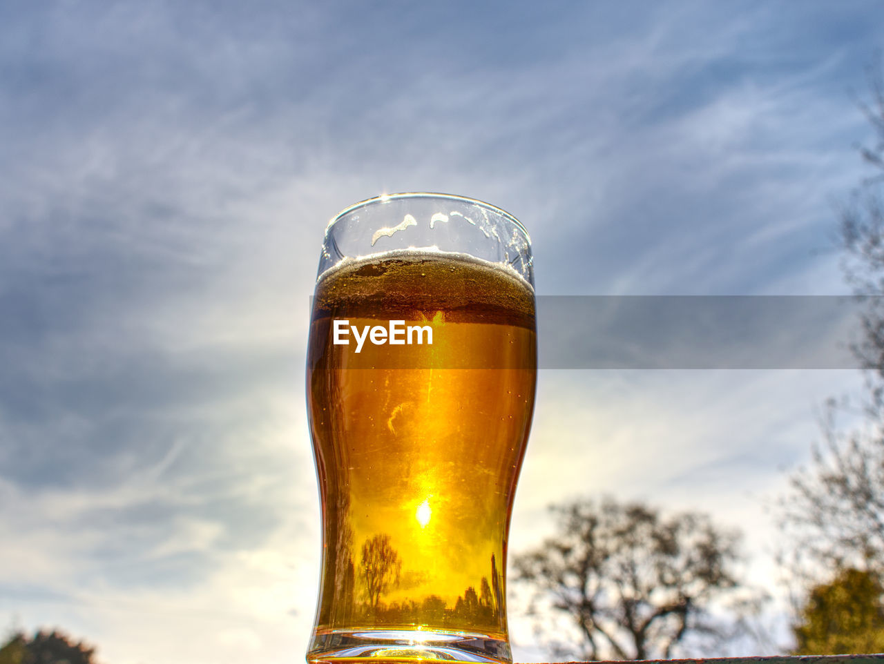 CLOSE-UP OF GLASS OF BEER AGAINST SKY