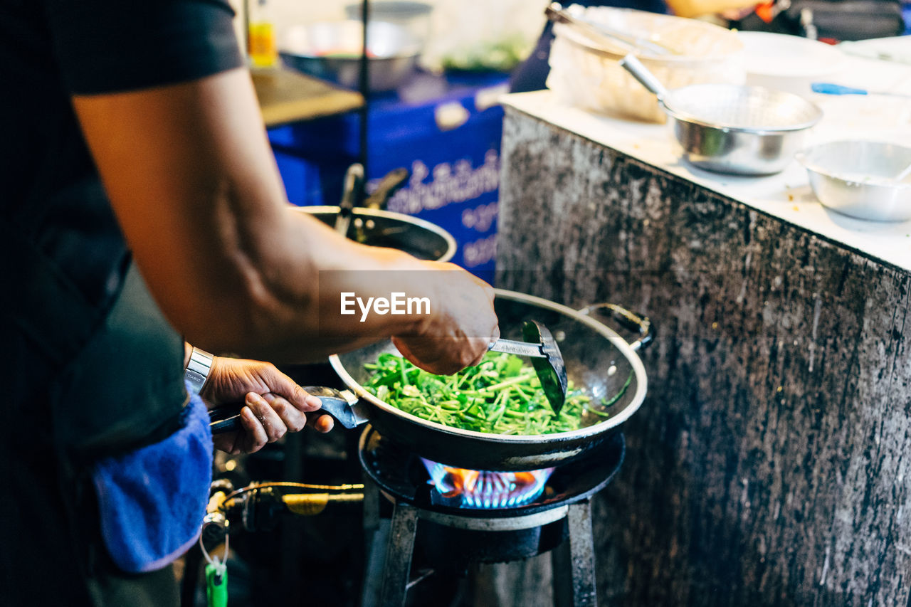 Man cooking fresh vegetables in a wok