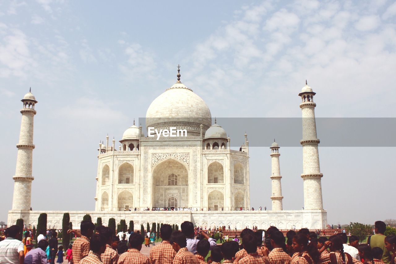 Large group of tourist looking at facade of taj mahal against sky