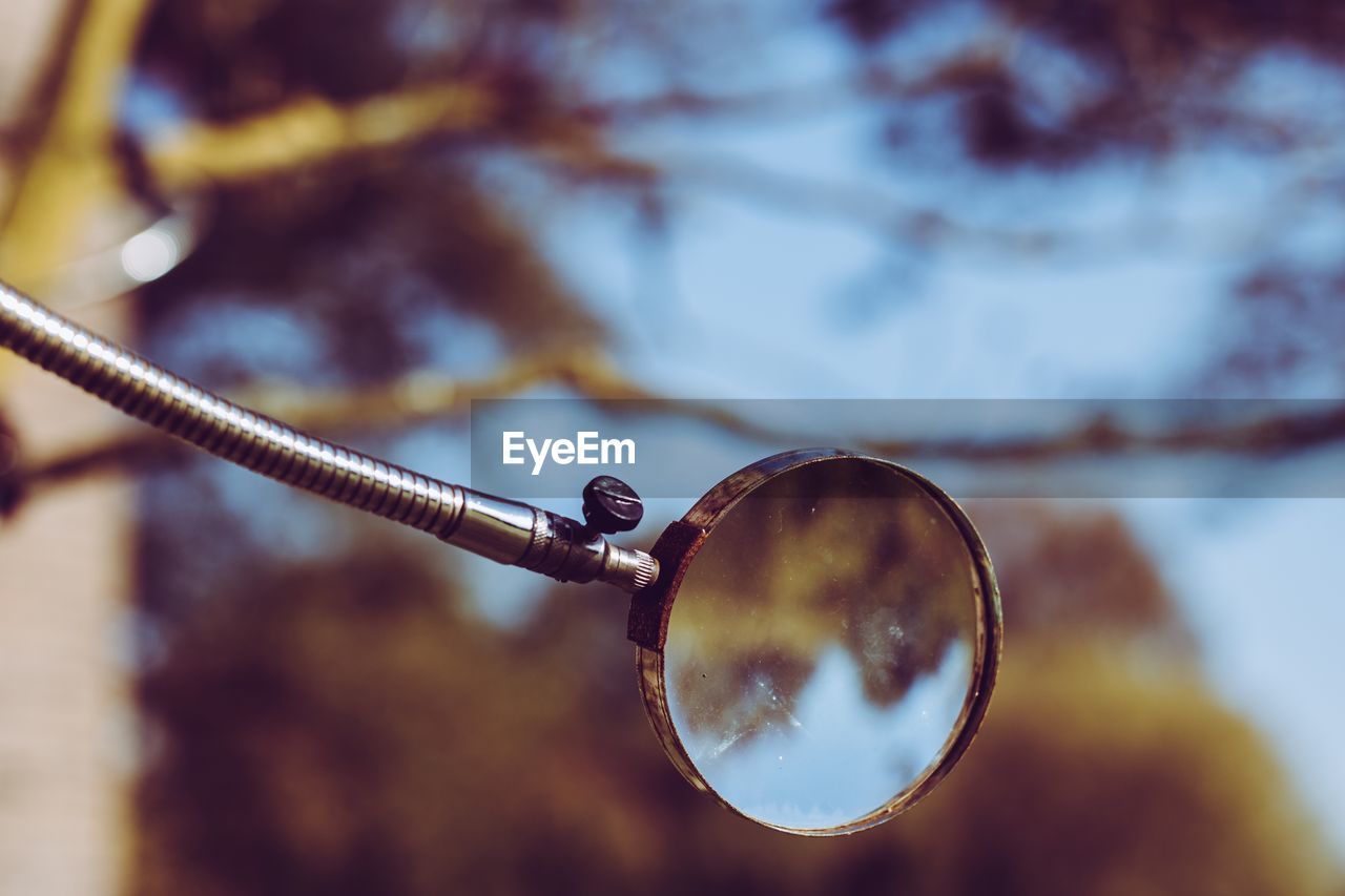 Close-up of magnifying glass against sky