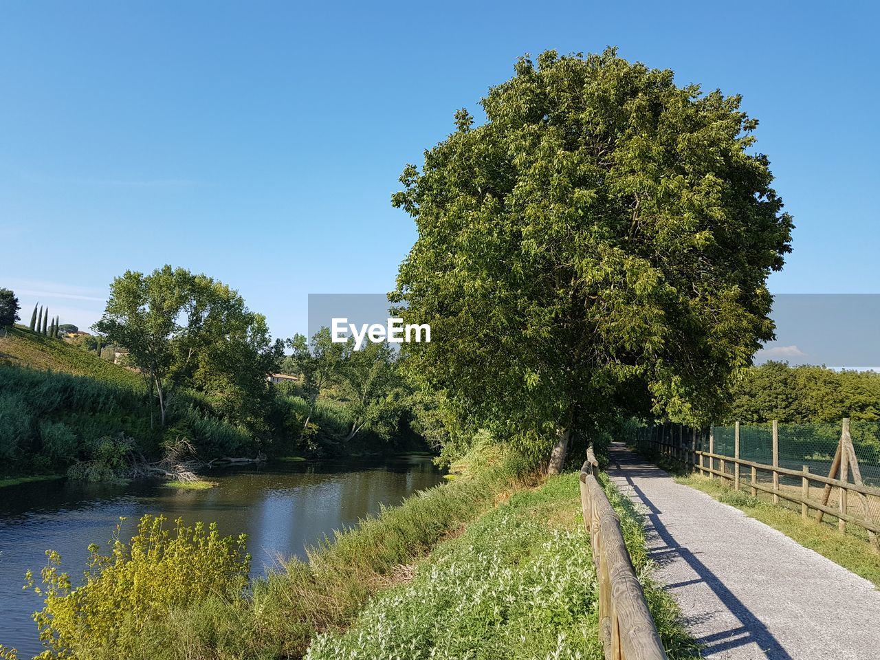 Scenic view of road through canal against clear sky