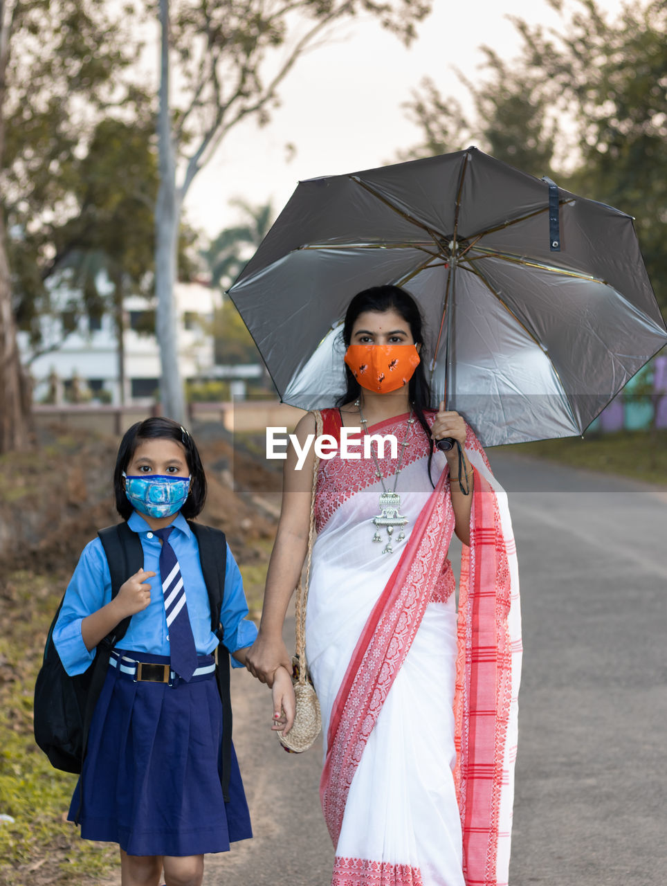 An indian school girl child going to school again after pandemic wearing nose mask protection