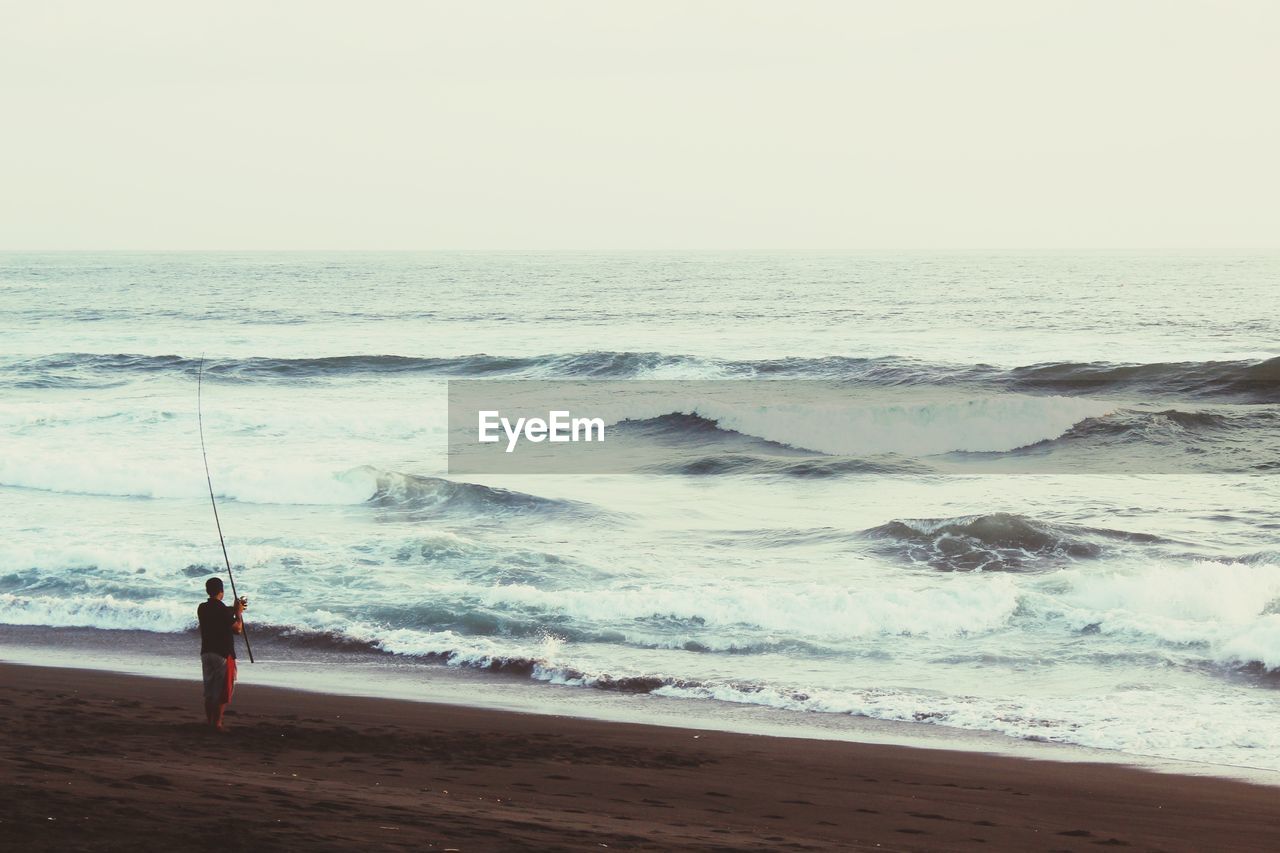 Rear view of man fishing at beach