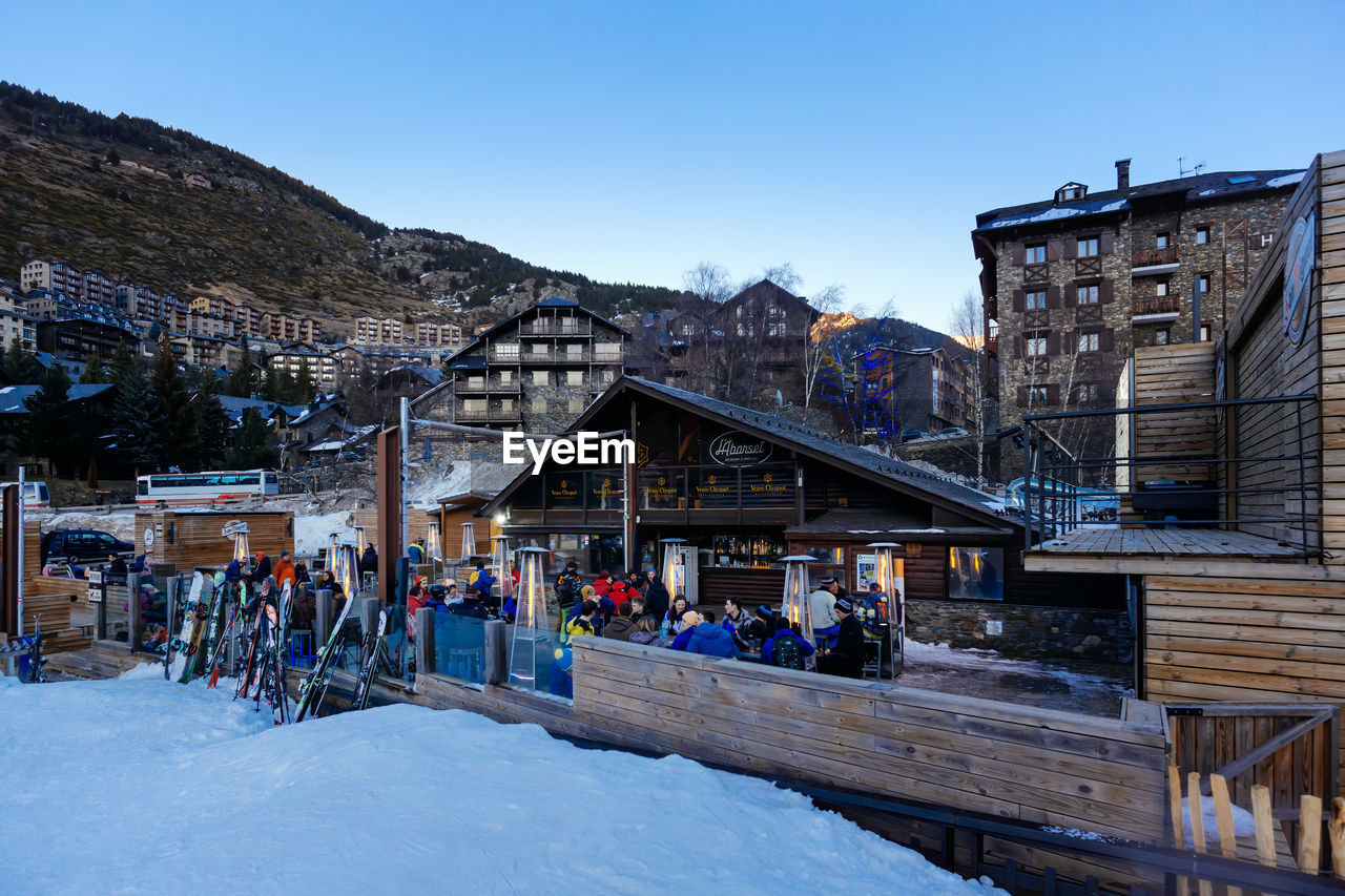 GROUP OF PEOPLE IN SNOW AGAINST BUILDINGS