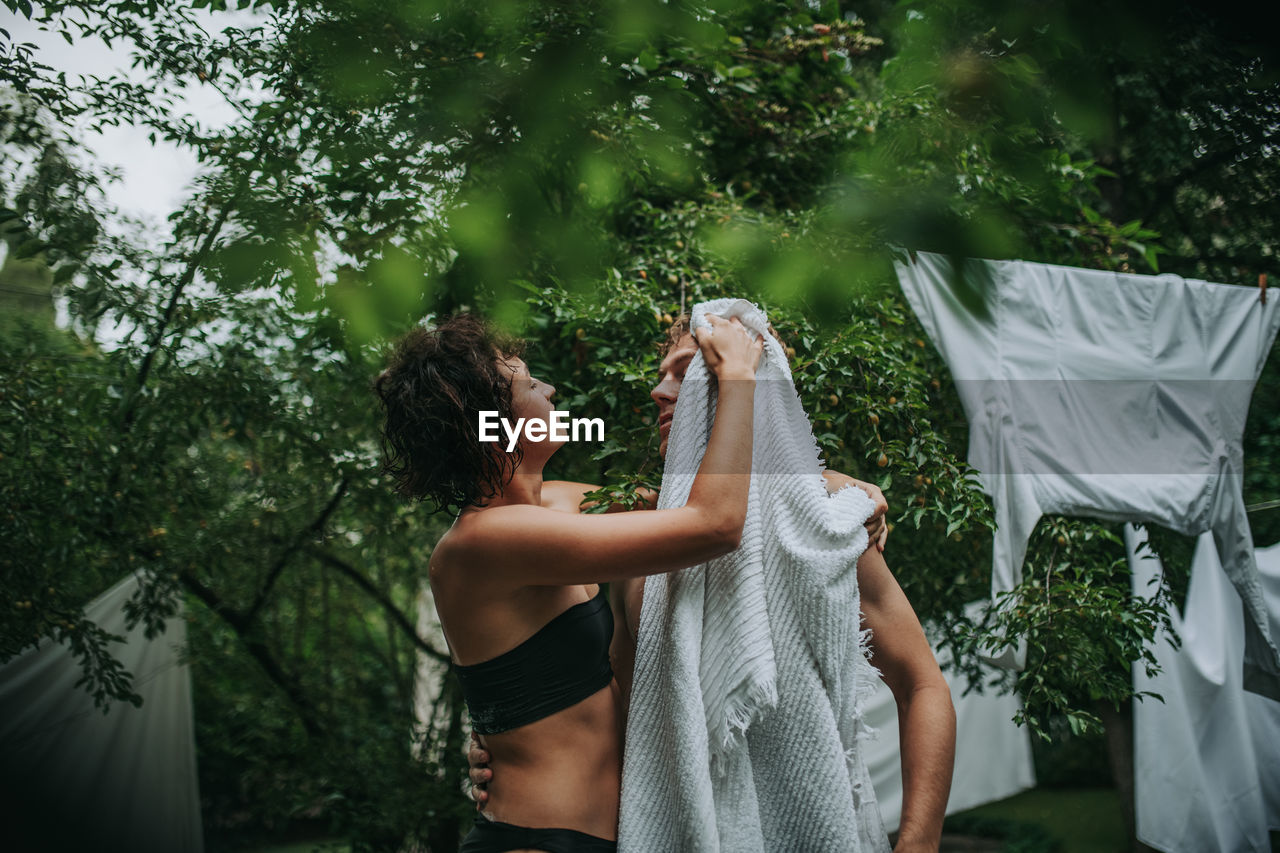 Couple with towel standing against trees