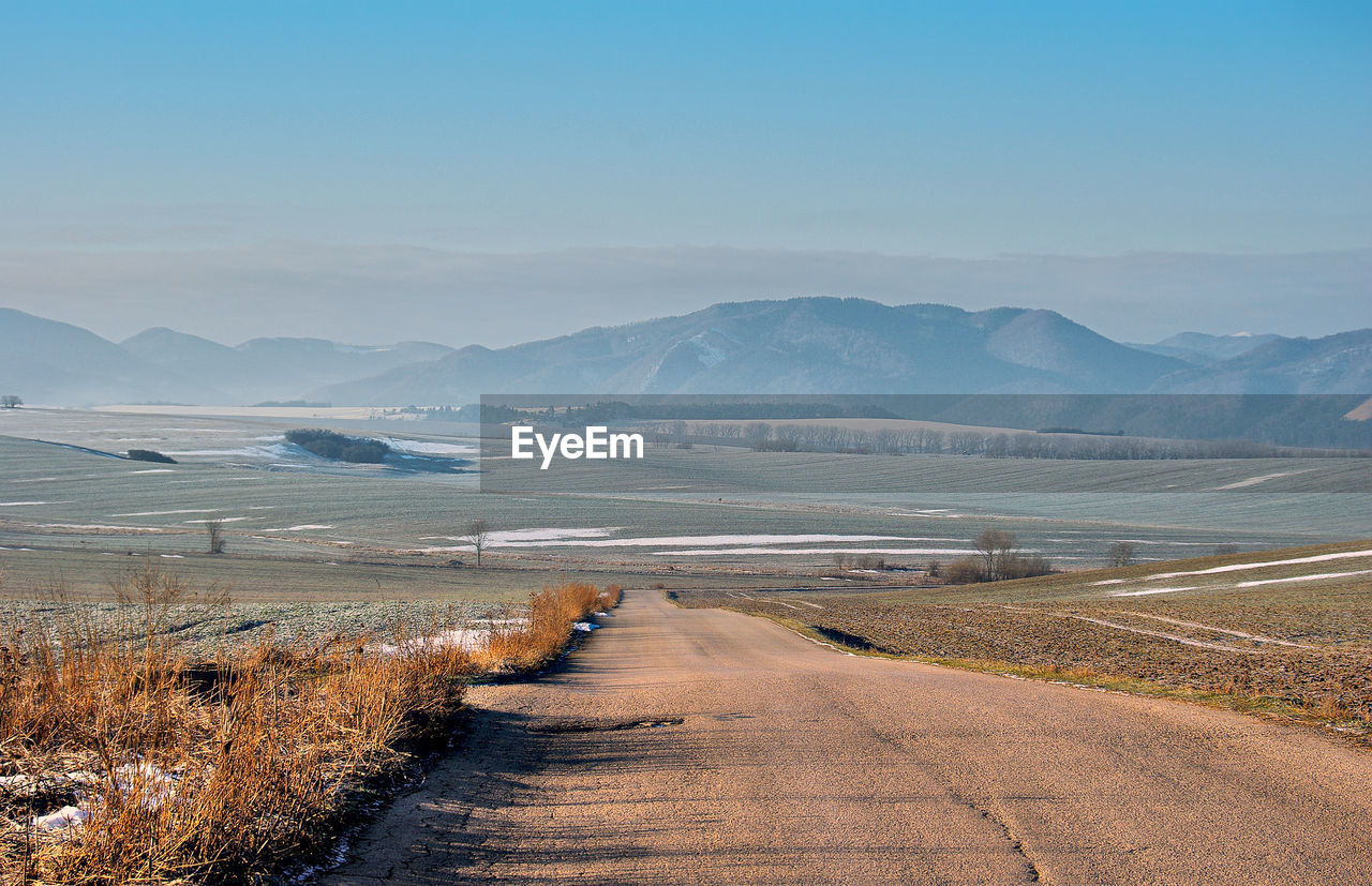 Scenic view of road by lake against sky