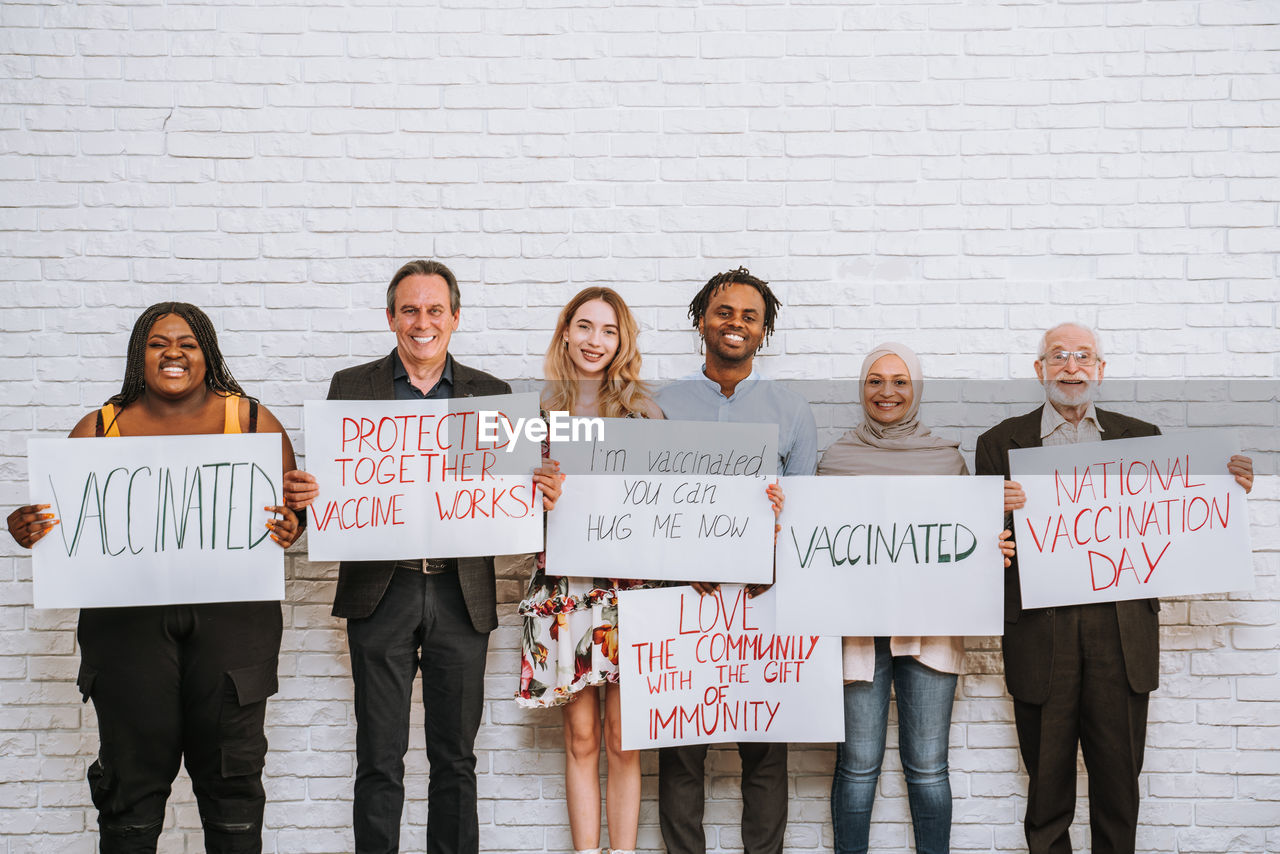 PORTRAIT OF FRIENDS STANDING AGAINST WALL IN A TEXT