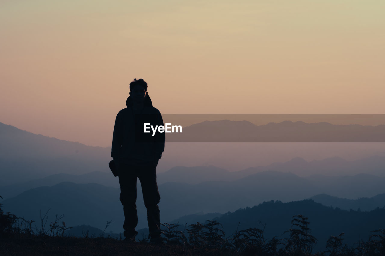 Silhouette man standing on mountain against sky