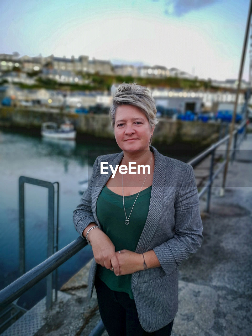 Portrait of smiling woman standing on bridge over river