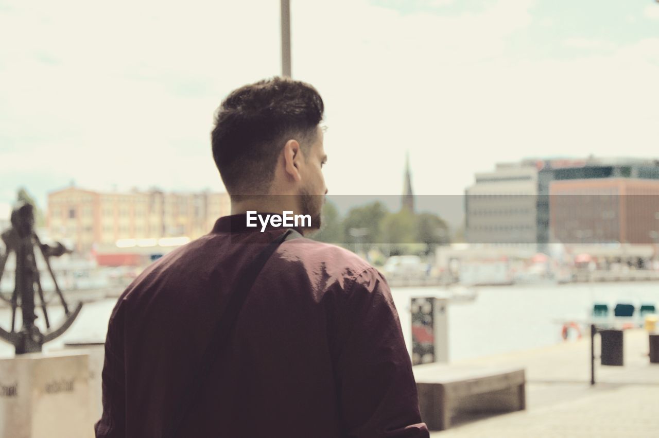 Rear view of man standing in city against sky