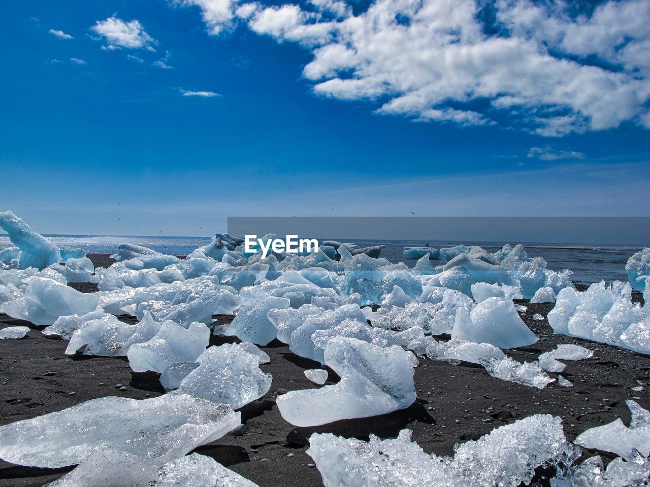 Glacial ice on sea shore against sky