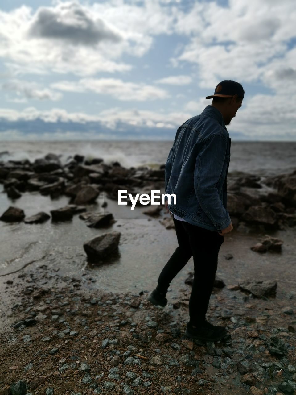 FULL LENGTH OF MAN STANDING ON ROCKS AT BEACH