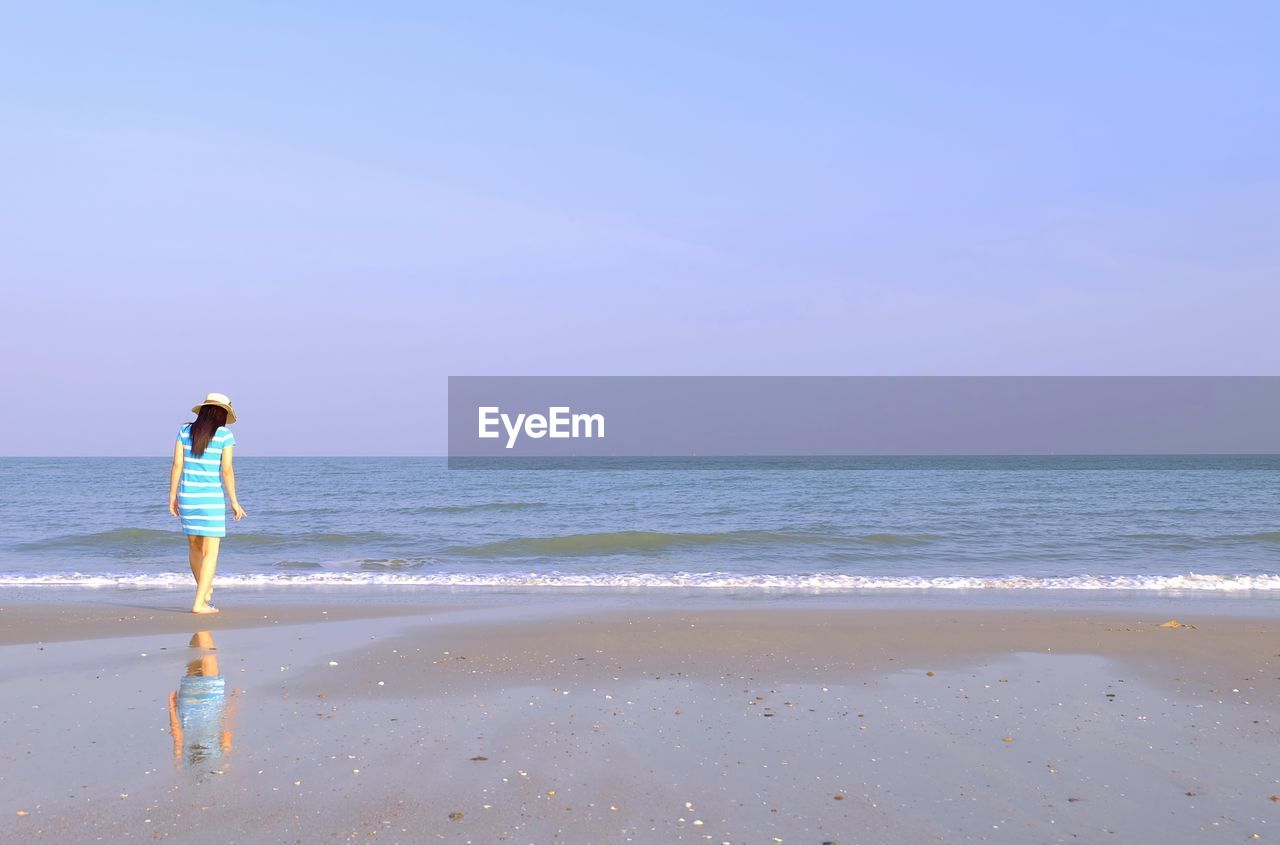 WOMAN STANDING ON BEACH