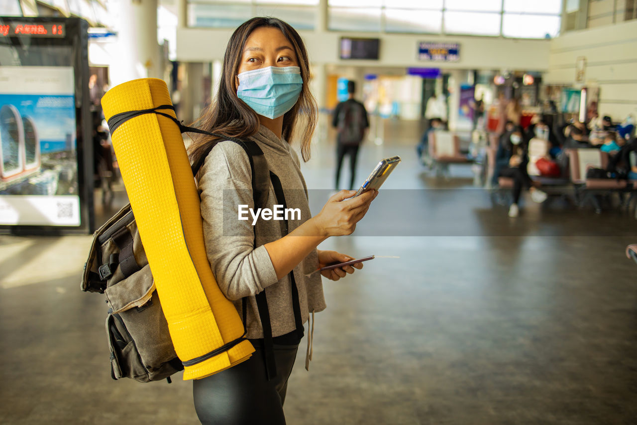 Chinese passenger with mask and smartphone in airport