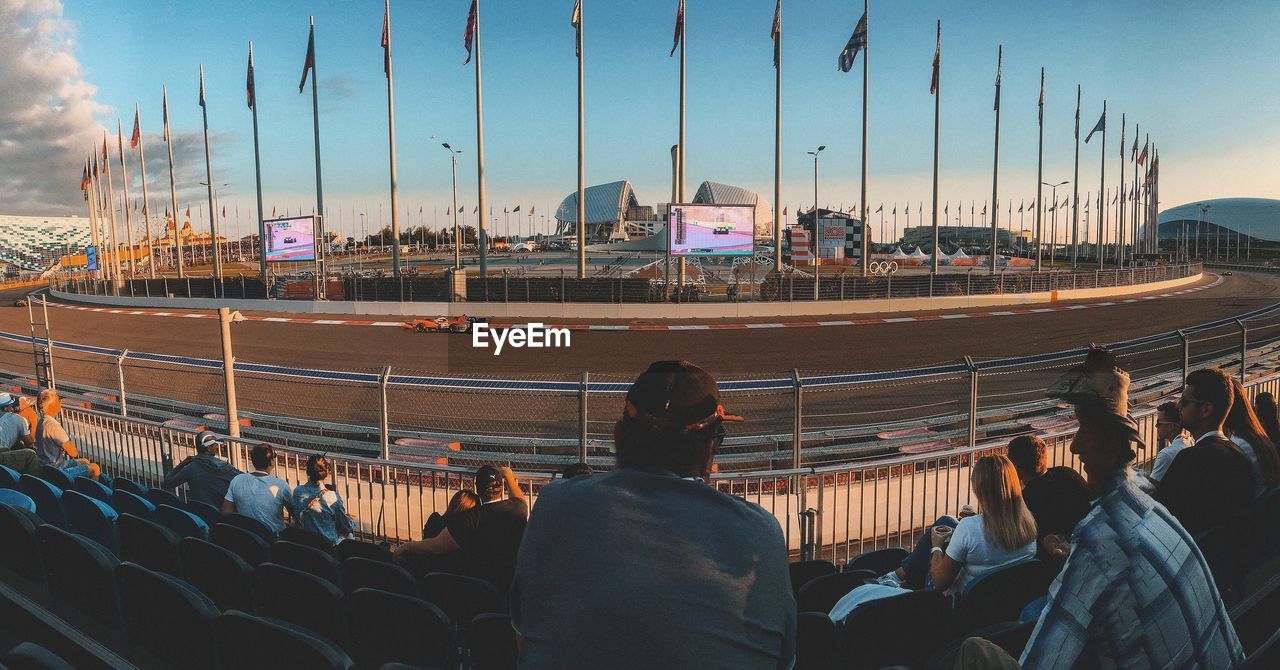 Rear view of people sitting by sports track