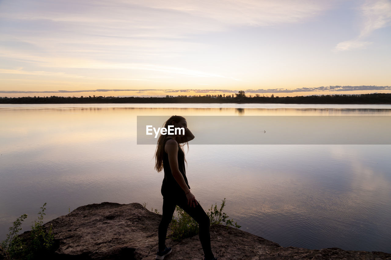 Traveler woman walking by the lake during sunset.