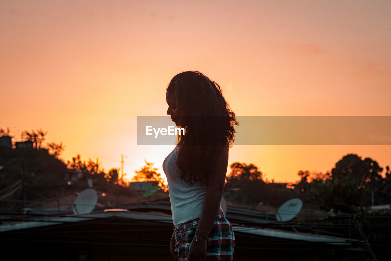 Rear view of woman standing against orange sky