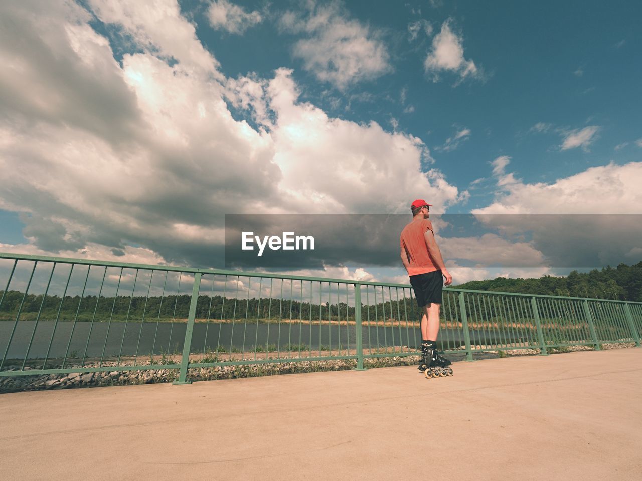 MAN STANDING BY RAILING AGAINST SKY