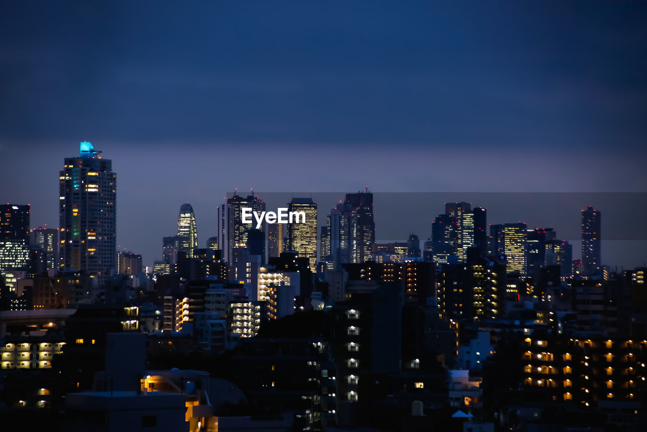 Illuminated buildings in city against sky at night