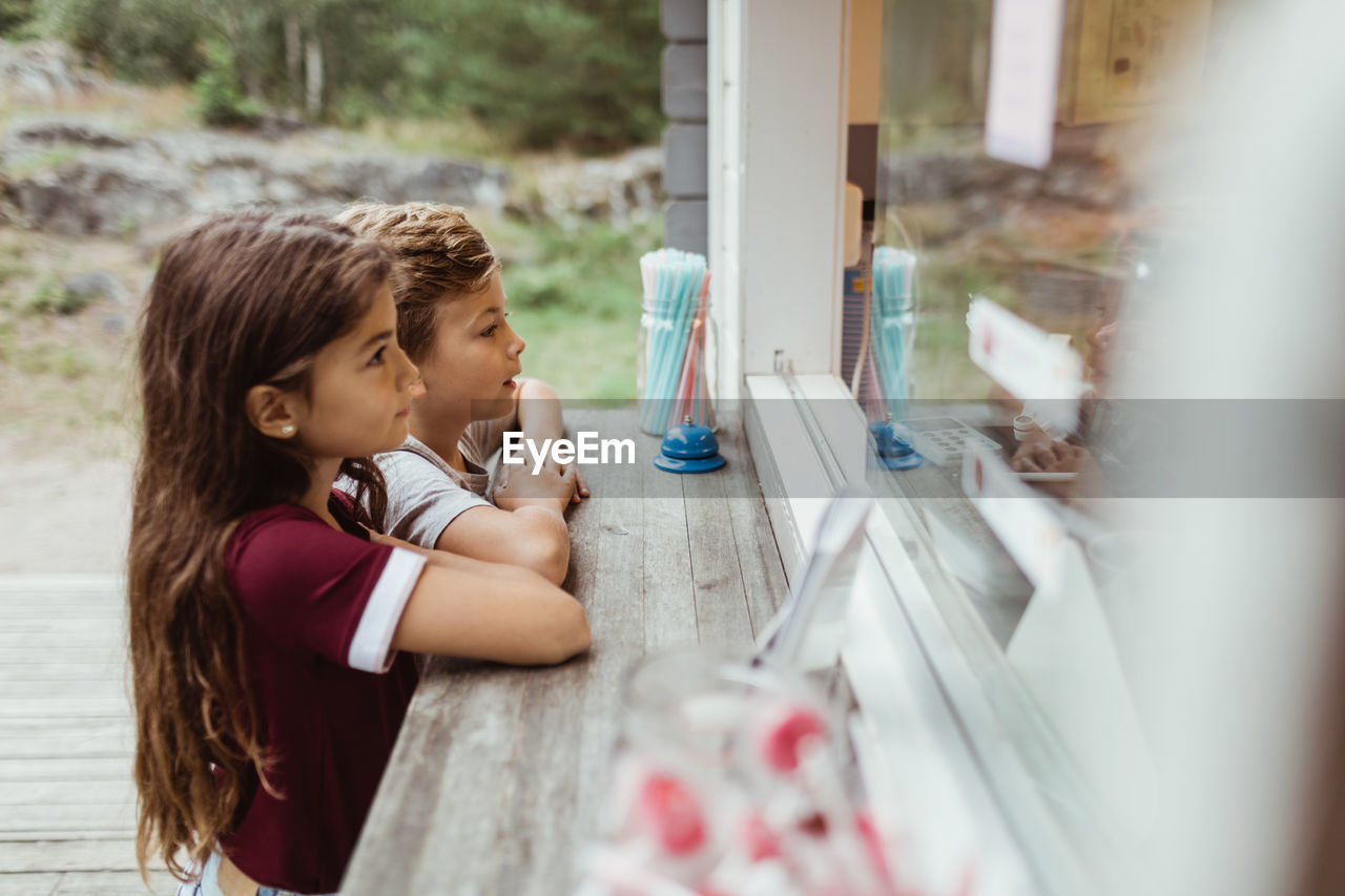 Side view of siblings standing by concession stand during vacation