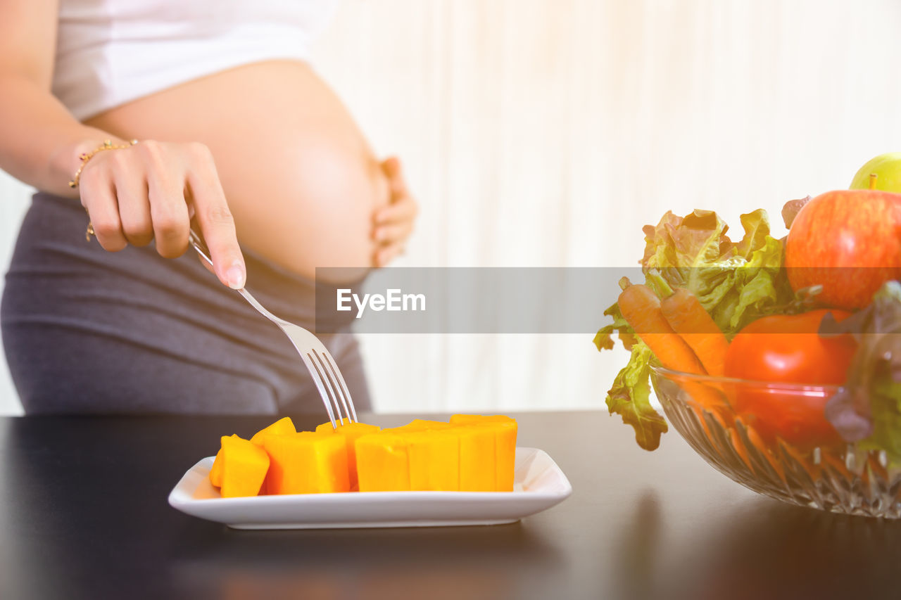 MIDSECTION OF WOMAN HOLDING FOOD