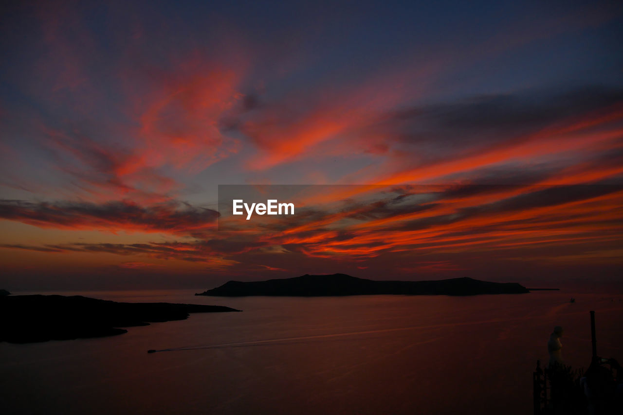 Scenic view of sea against dramatic sky during sunset