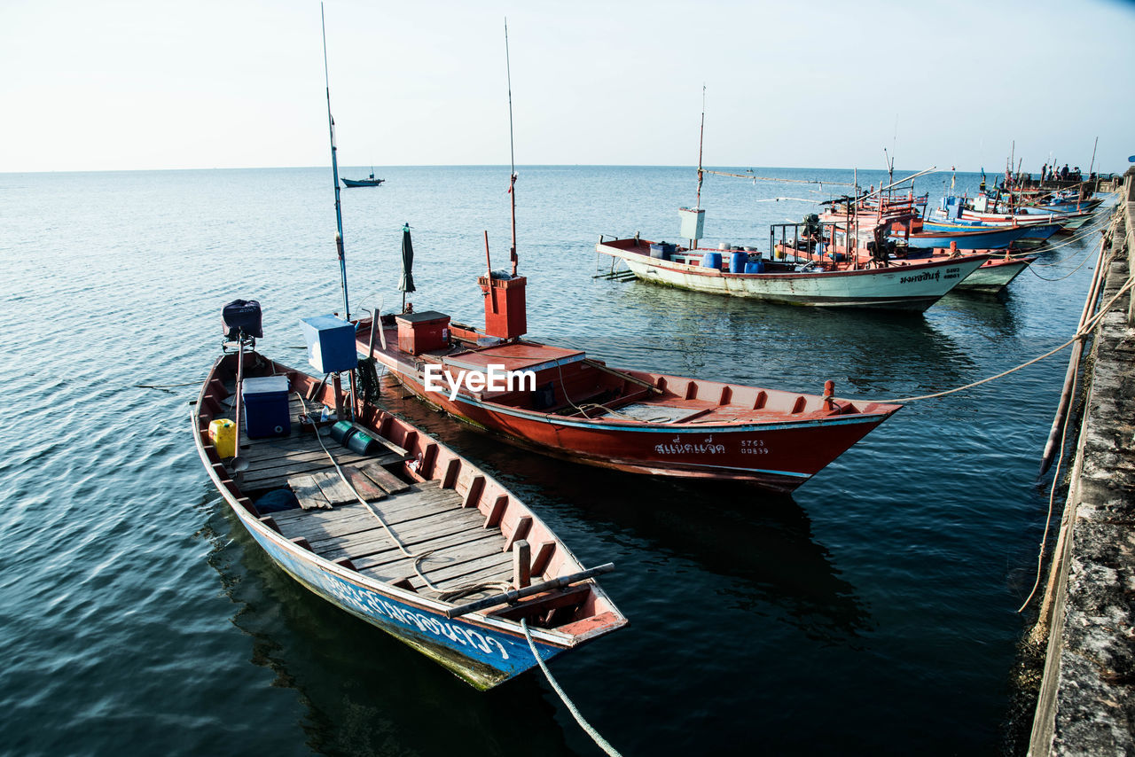 Boats moored in sea against clear sky