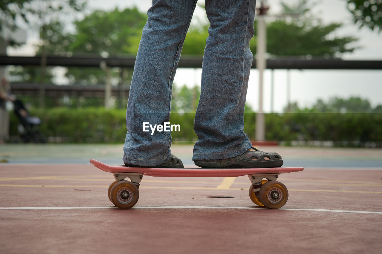 Close-up of female legs in jeans on a penny board skateboard outdoors