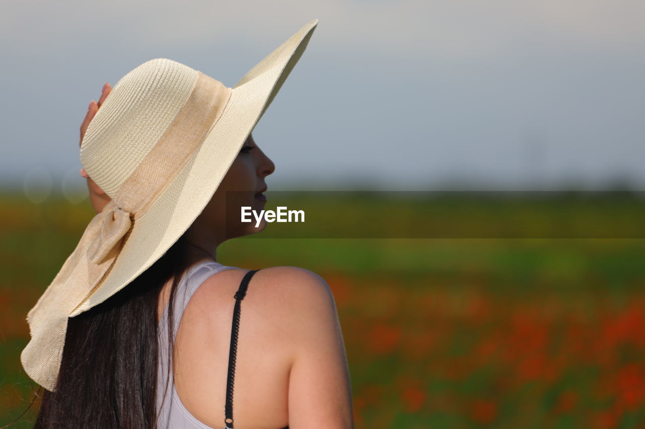 Rear view of woman wearing hat while standing on field