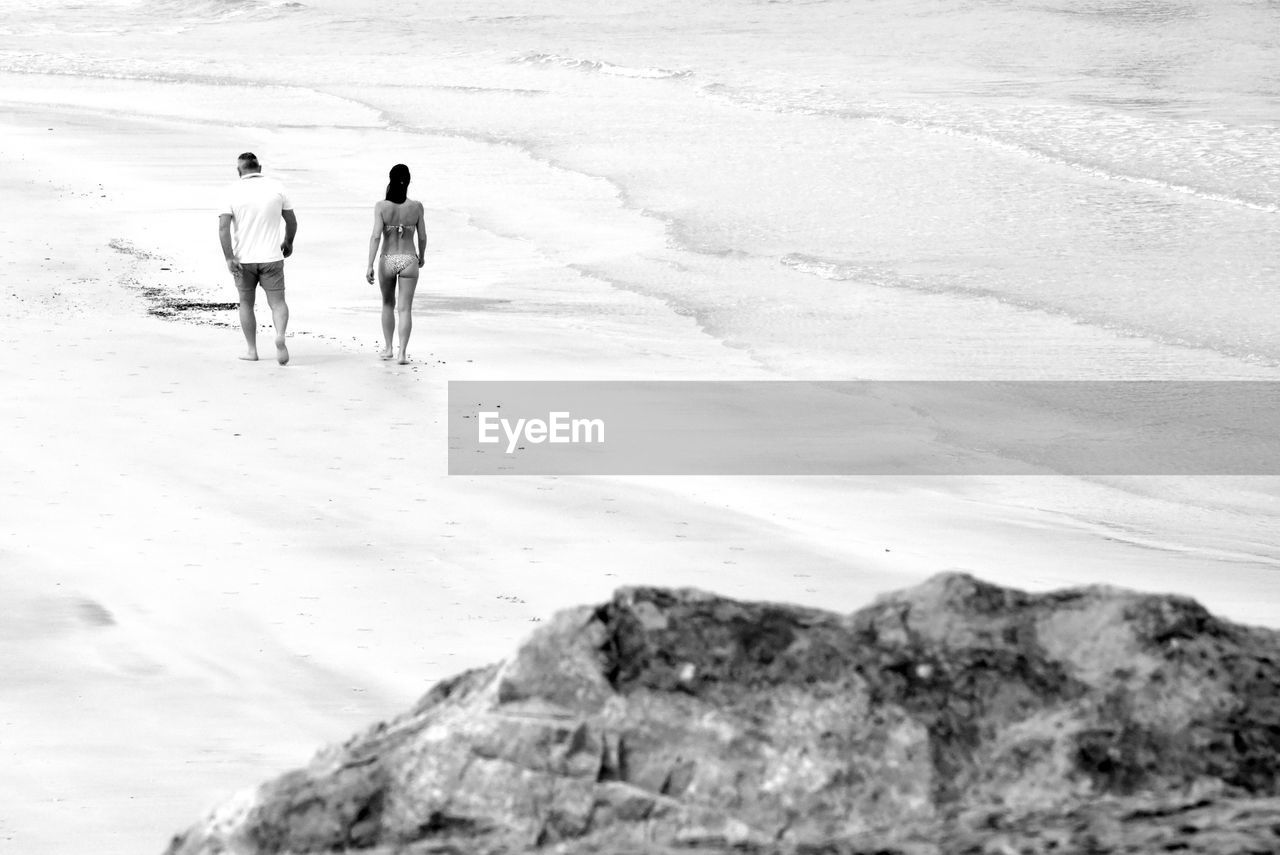 Rear view of couple walking at beach