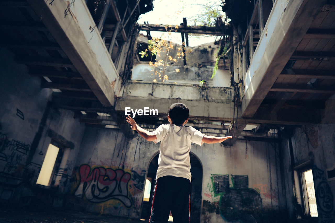 Rear view of boy standing at abandoned building