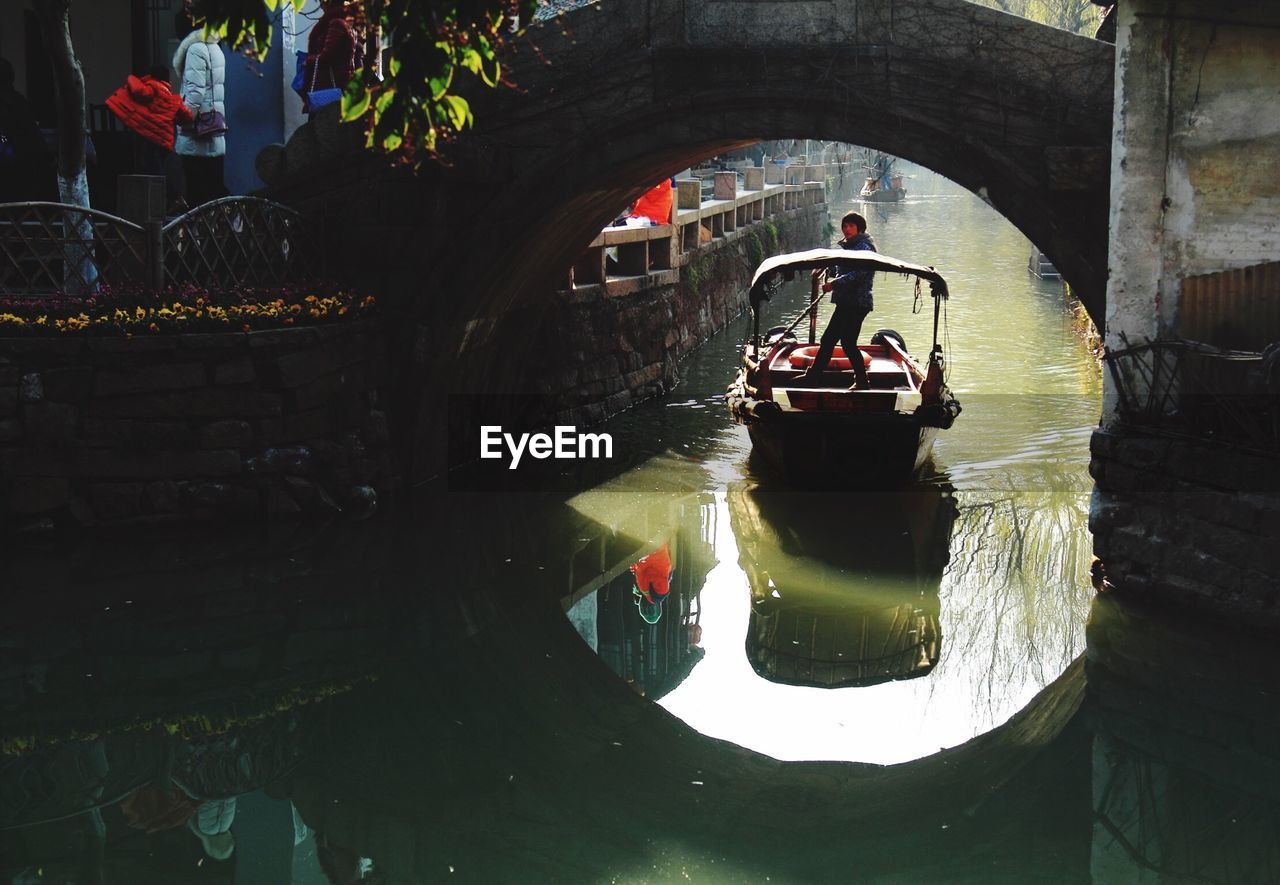 High angle view of man on boat below bridge at canal