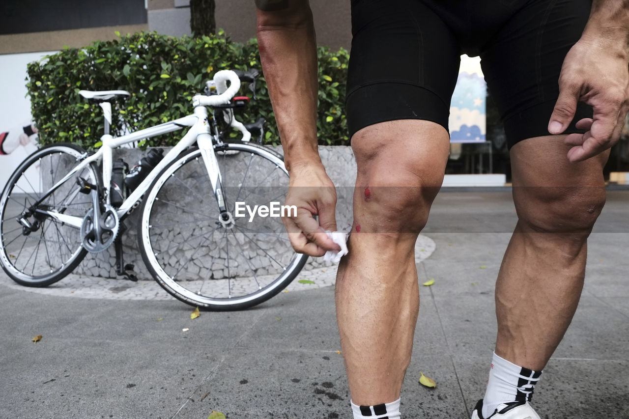 LOW SECTION VIEW OF MAN WITH BICYCLE