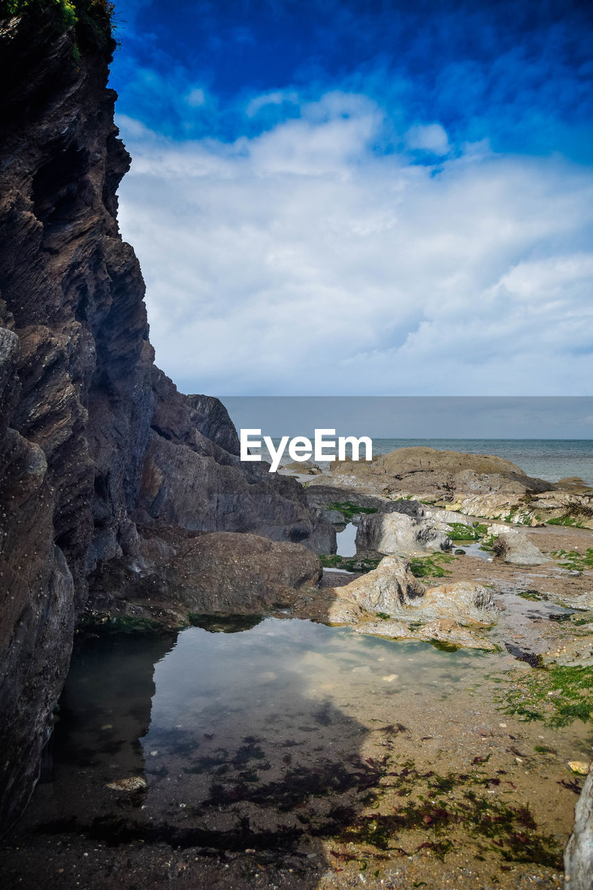 SCENIC VIEW OF ROCKS ON BEACH AGAINST SKY