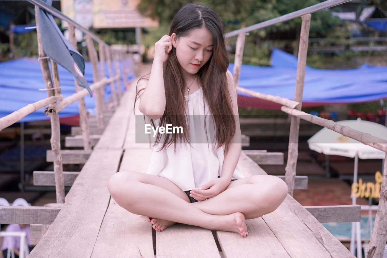 Beautiful young woman sitting on footbridge