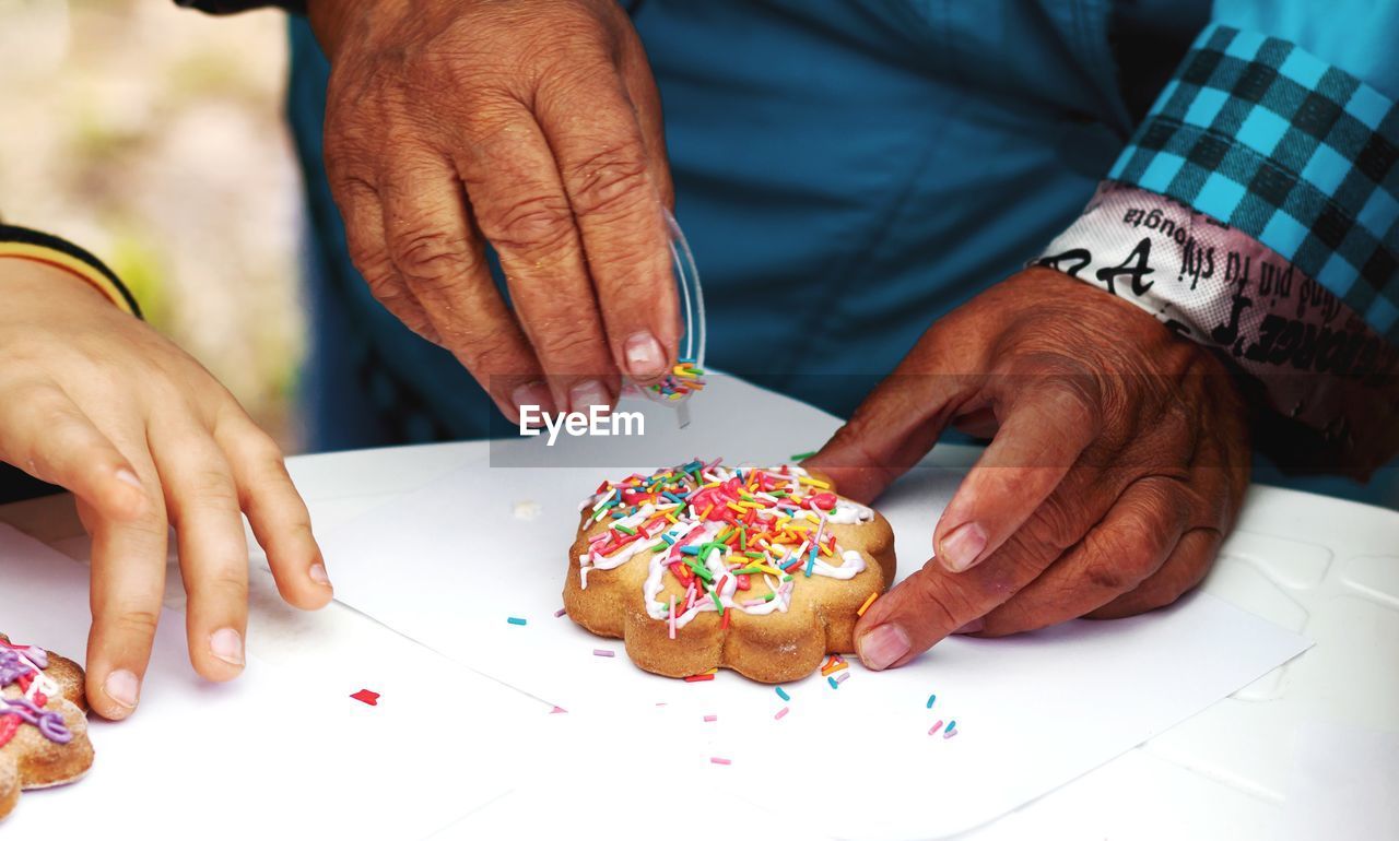Only hands. aged woman decorates cookies.