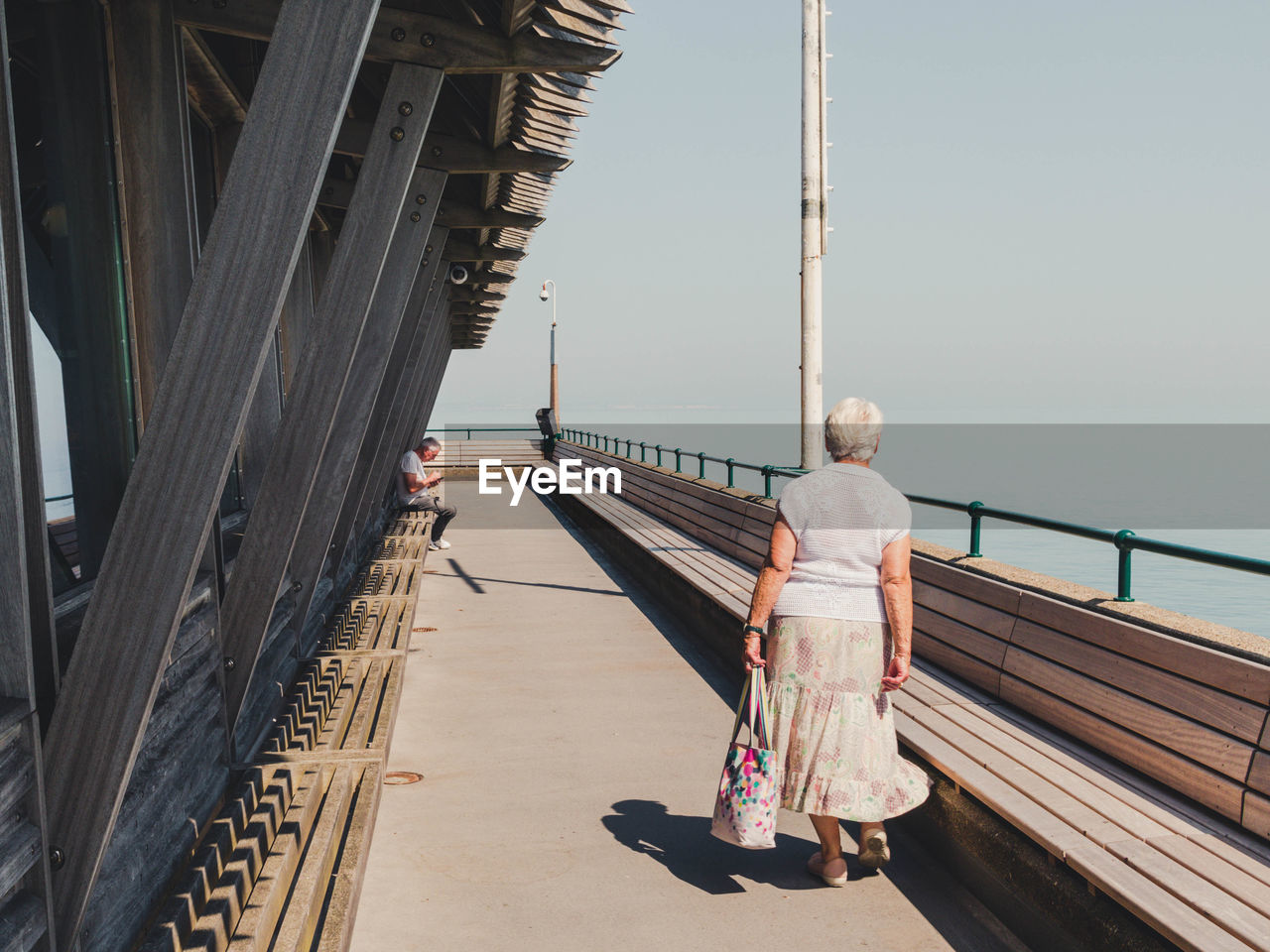 Rear view of woman on footbridge against sky