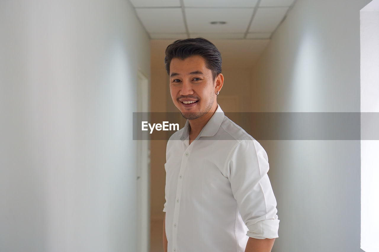 Portrait of smiling man standing amidst wall