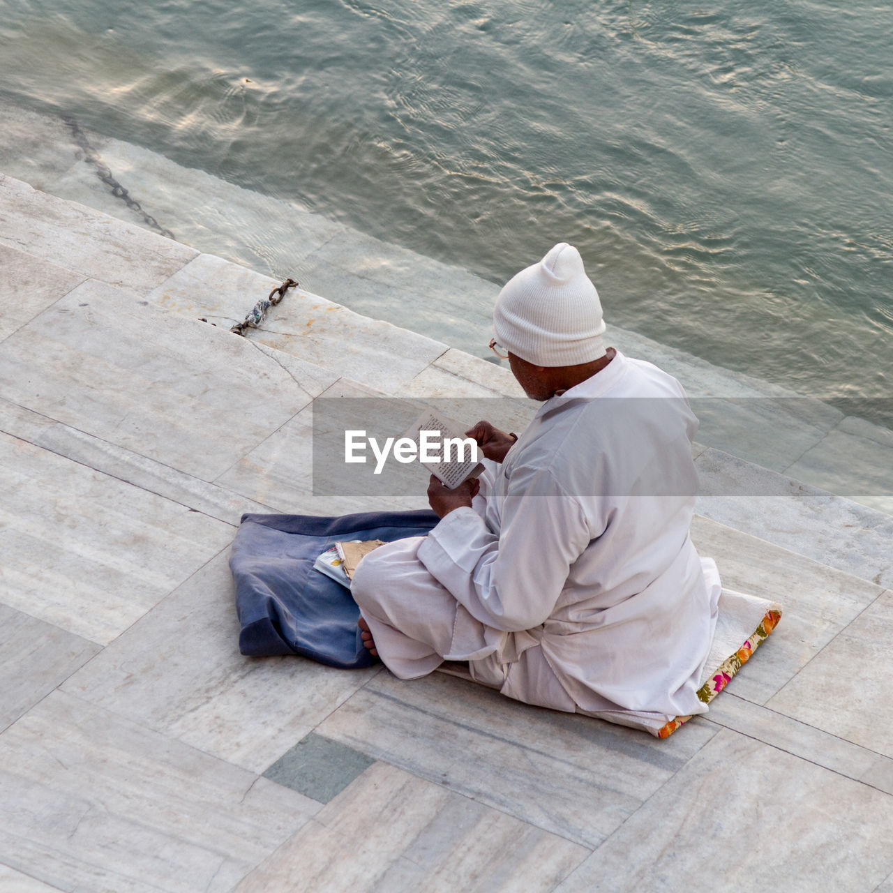 HIGH ANGLE VIEW OF MAN SITTING ON WATER