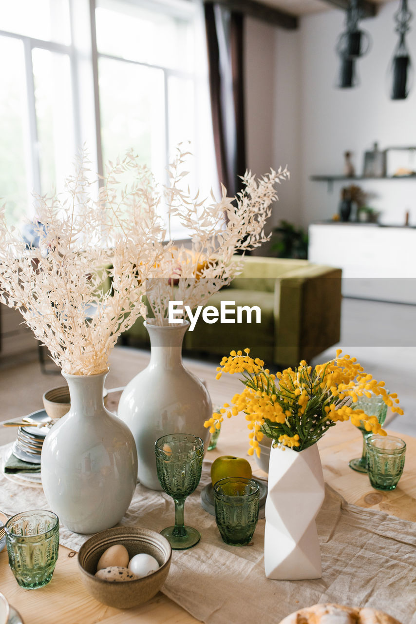 Festive easter table with mimosa flowers in a vase and traditional food, eggs