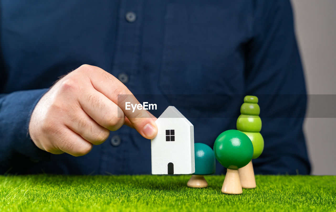 A man places a house figurine on a plot of land. build a new house on the plot.