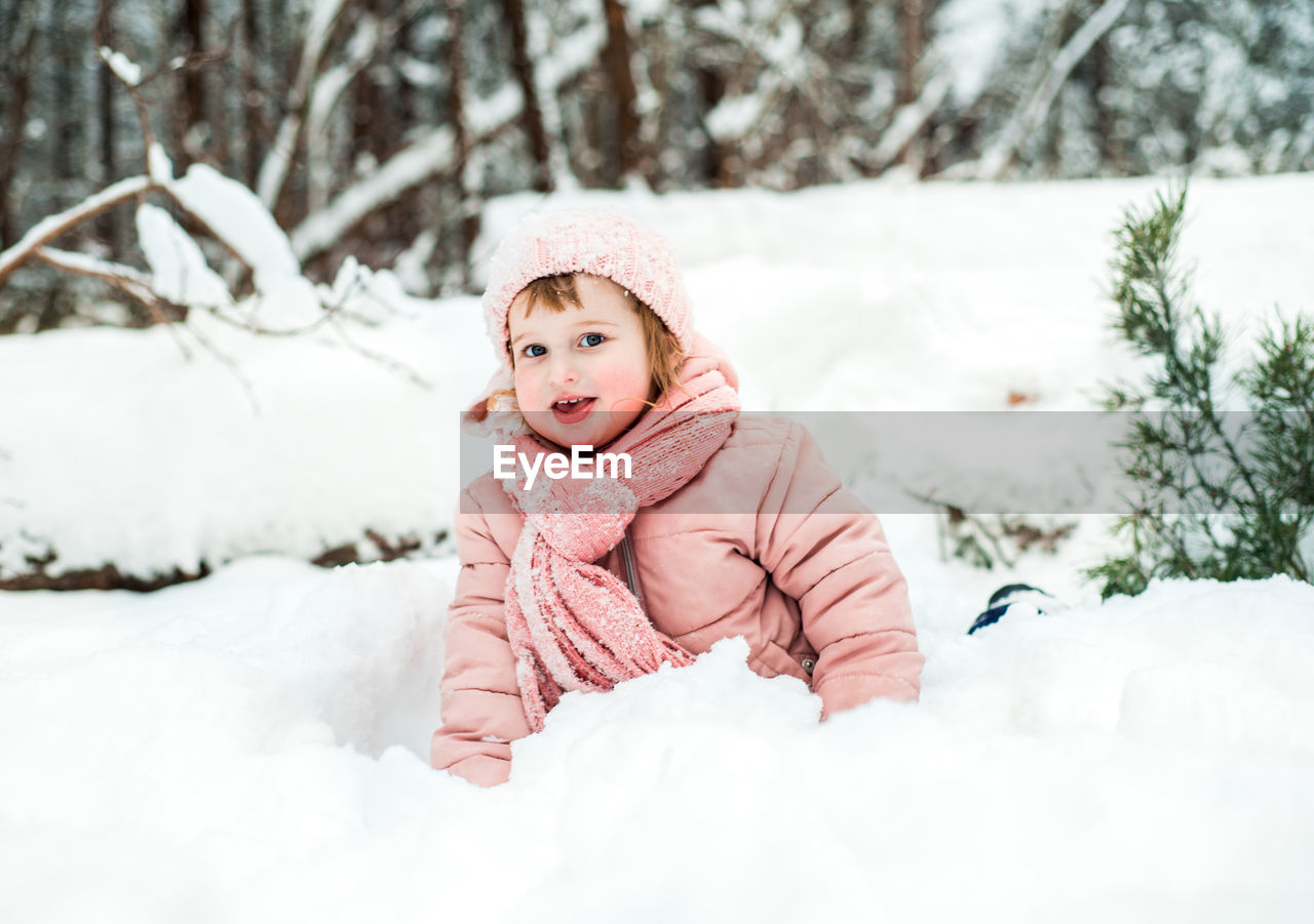 Portrait of cute girl playing with snow during winter