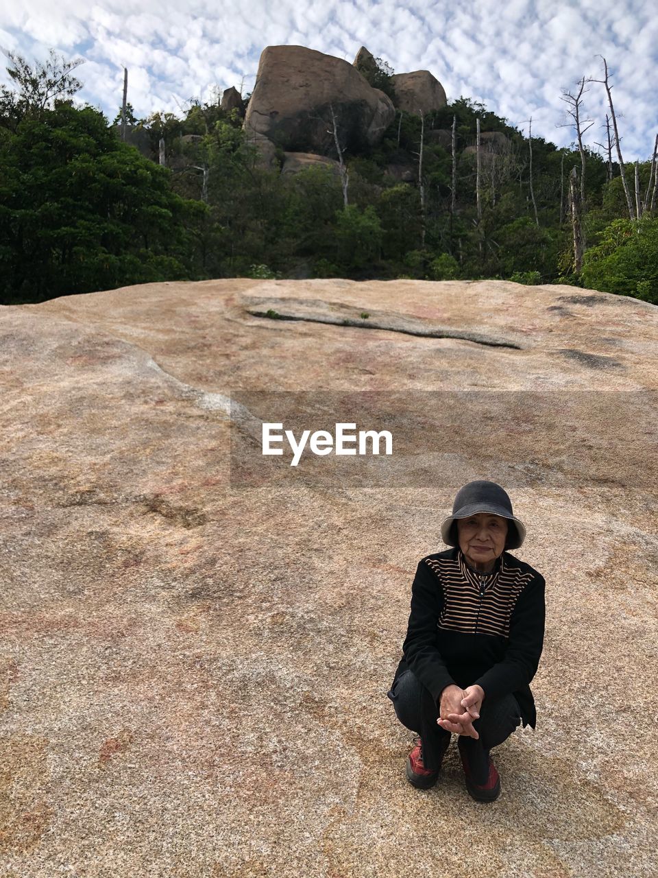 Portrait of senior woman crouching on mountain