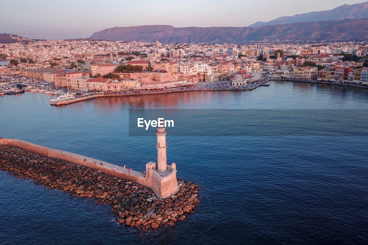 Aerial view of townscape by sea against sky during sunset