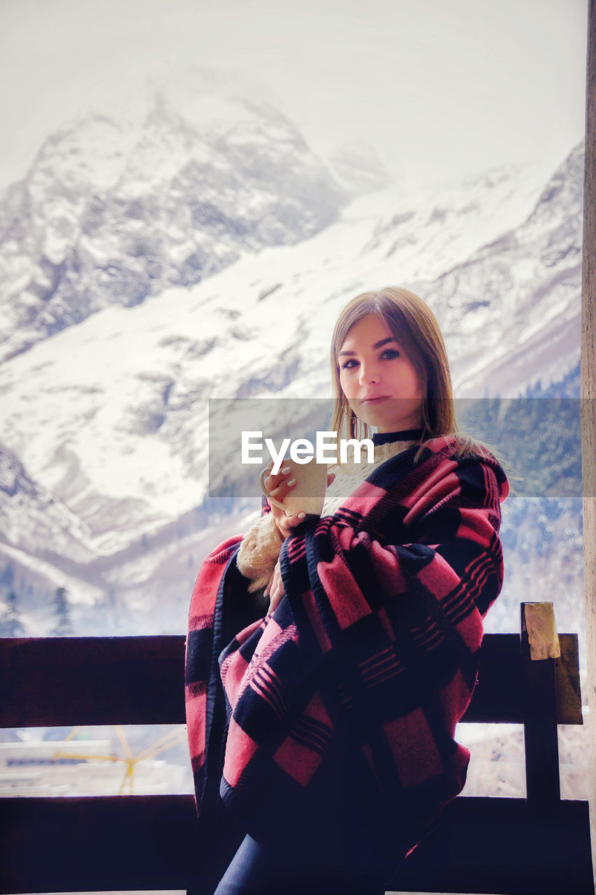 Portrait of woman standing on snow covered mountain