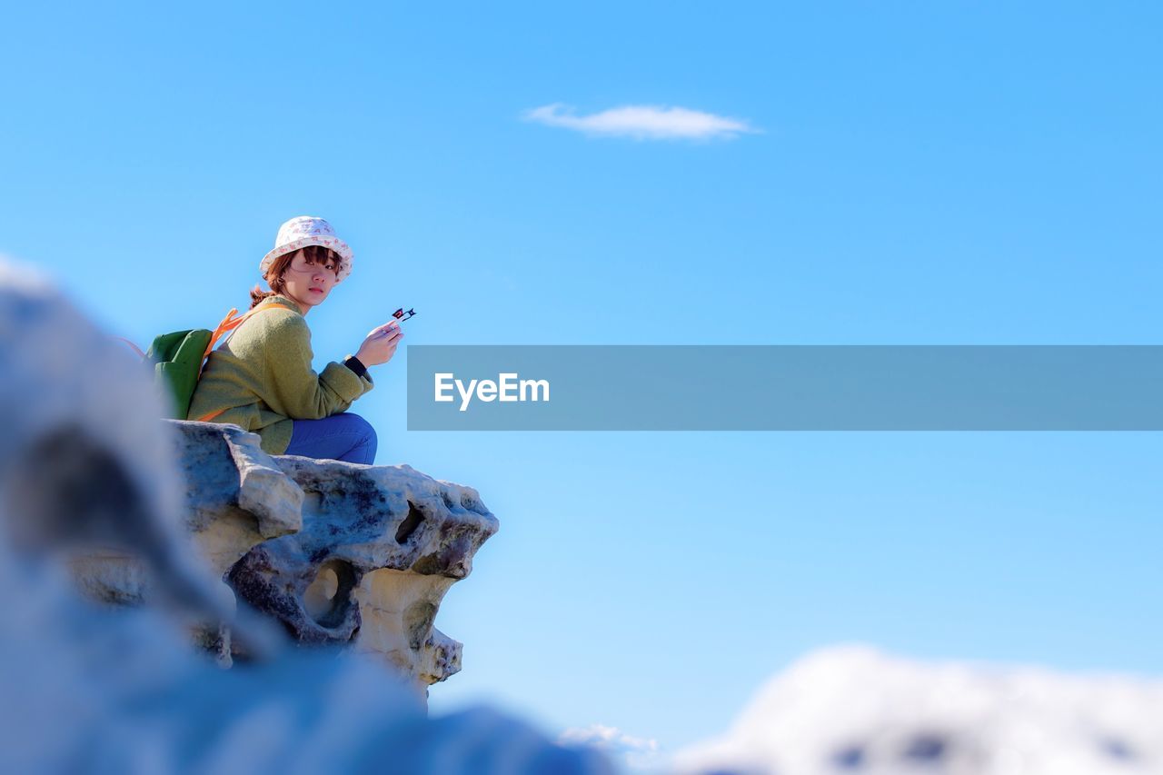 Low angle view of tourist against blue sky