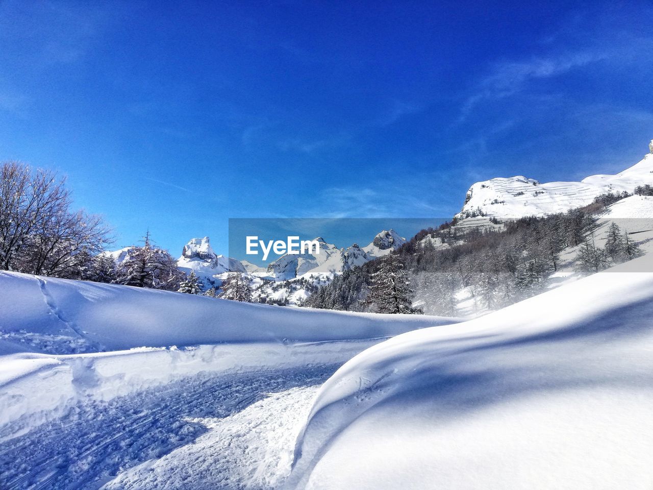 Snow covered landscape against blue sky