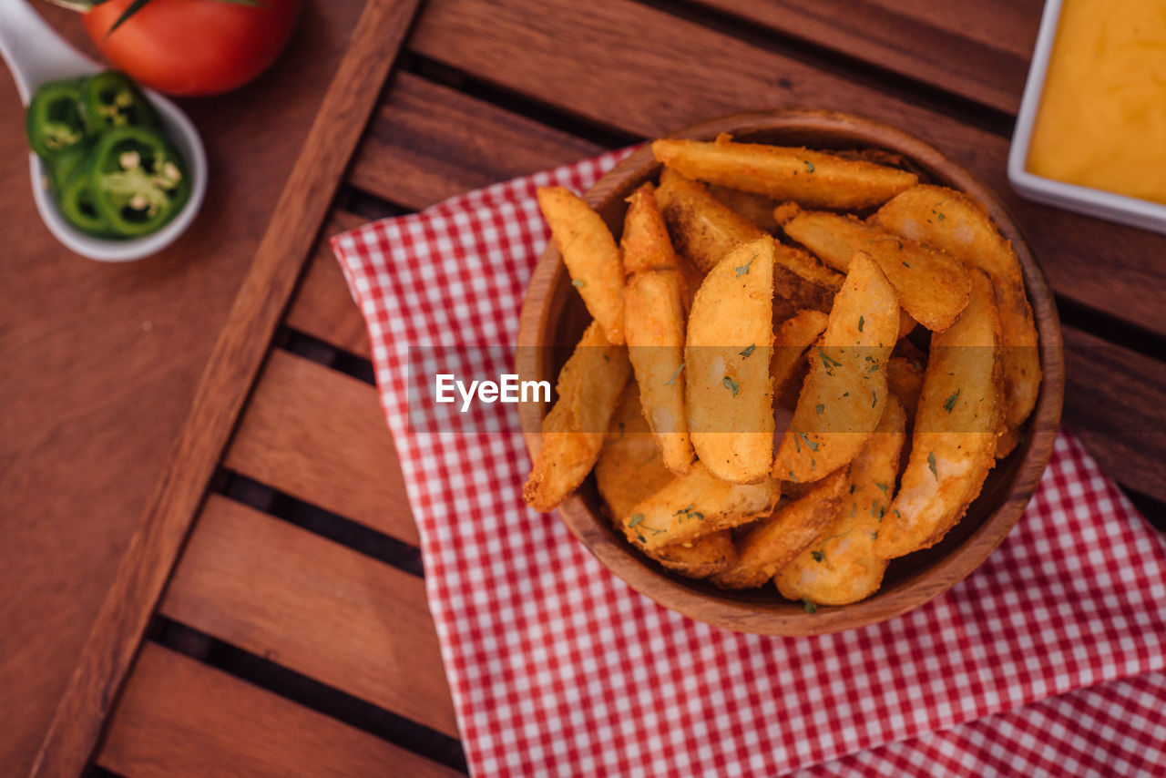 High angle view of fried potatoes in bowl on wooden table
