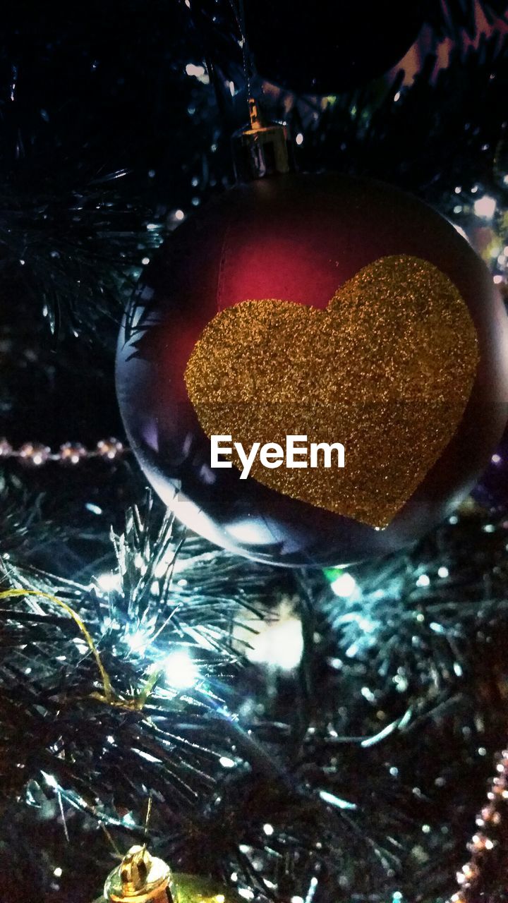 Close-up of heart shape on bauble hanging from christmas tree